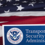 TSA Chaos Hits Major Airports Transportation Security Administration sign in front of an American flag