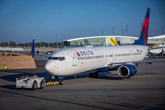 Delta airplane being towed at airport terminal gate.
