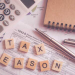 Calculator and tax documents with wooden letters spelling 'TAX SEASON'