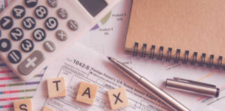 Calculator and tax documents with wooden letters spelling 'TAX SEASON'