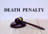 A wooden gavel resting on a block with the words 'DEATH PENALTY' in bold above it