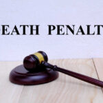 A wooden gavel resting on a block with the words 'DEATH PENALTY' in bold above it