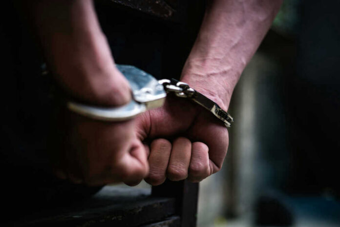 Close-up of hands in handcuffs behind back.