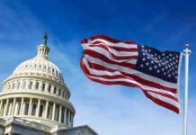 US Capitol with American flag waving in foreground.