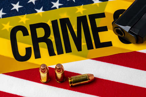 shutterstock_1979269220.jpg A gun and bullets on an American flag with a crime scene marker