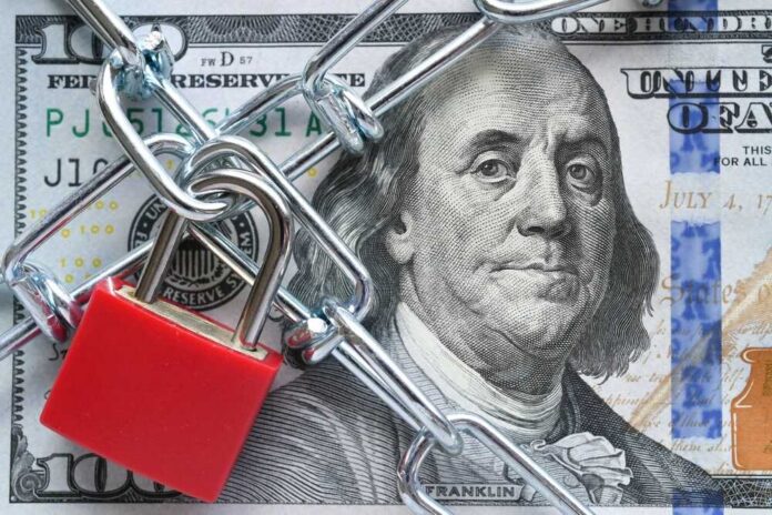 shutterstock_2297559635.jpg A red padlock and chain over a hundred dollar bill featuring Benjamin Franklin