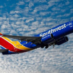 Southwest airplane on the air with blu sky and white clouds.