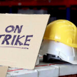 Sign reads On Strike near yellow hardhat