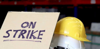 Sign reads On Strike near yellow hardhat