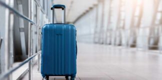 A blue suitcase with wheels positioned in an airport terminal