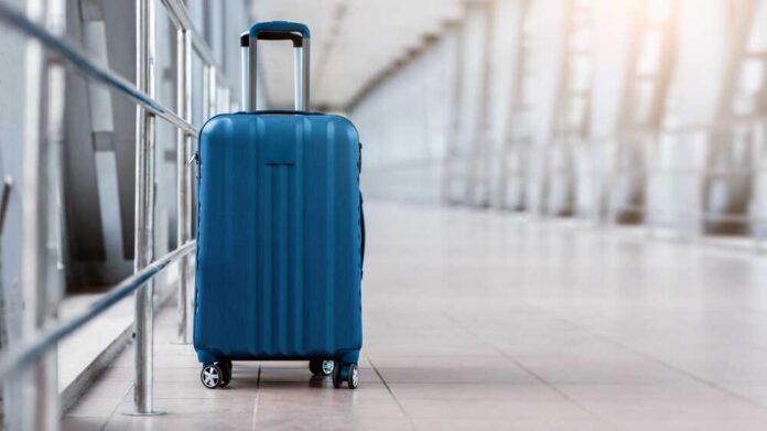A blue suitcase with wheels positioned in an airport terminal