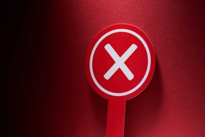 Red sign with a white cross symbol on a dark background