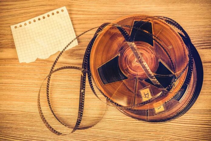 shutterstock_2694909889.jpg A vintage film reel with a piece of graph paper beside it