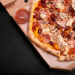 A pizza with various toppings in a delivery box