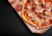 A pizza with various toppings in a delivery box