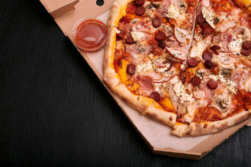 A pizza with various toppings in a delivery box