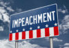 A sign displaying the word 'IMPEACHMENT' against a cloudy sky