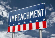 A sign displaying the word 'IMPEACHMENT' against a cloudy sky