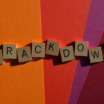 Wooden letter tiles spelling 'CRACKDOWN' on a colorful background