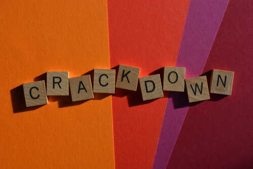 Wooden letter tiles spelling 'CRACKDOWN' on a colorful background