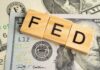 Wooden letters spelling 'FED' on top of U.S. dollar bills