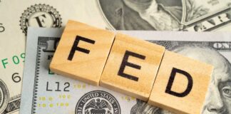 Wooden letters spelling 'FED' on top of U.S. dollar bills