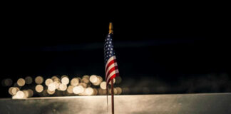 American flag above engraved Pentagon sign at night
