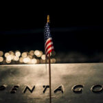 American flag above engraved Pentagon sign at night