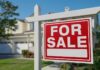 A 'For Sale' sign in front of a house