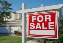 A 'For Sale' sign in front of a house