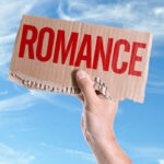 Shocking Romance Deficit: Women Hit Hardest A hand holding a cardboard sign that reads 'ROMANCE' against a blue sky