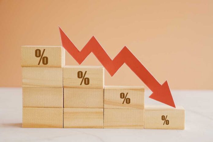 Wooden blocks with percentage symbols and a downward arrow indicating decline