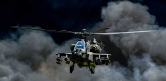 Military helicopter flying through a cloud of smoke