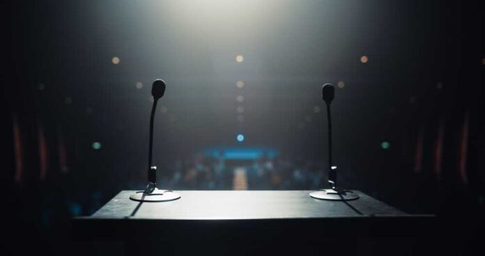View of a podium with microphones in a dimly lit auditorium