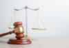 A wooden gavel in front of a balance scale symbolizing justice