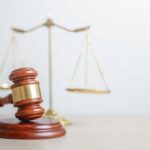 A wooden gavel in front of a balance scale symbolizing justice