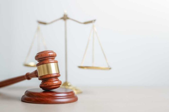 A wooden gavel in front of a balance scale symbolizing justice