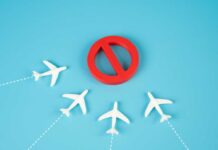 A red prohibition sign surrounded by white airplane models on a blue background