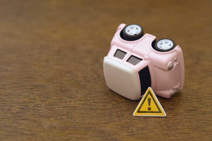 Upside down pink toy car next to a warning sign