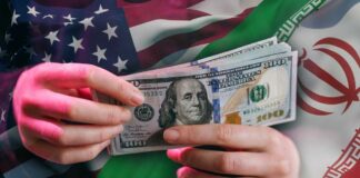Hands holding a $100 bill with American and Iranian flags in the background