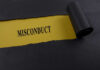 Torn black paper revealing the word 'MISCONDUCT' on yellow paper