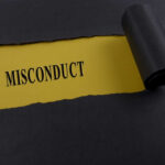 Torn black paper revealing the word 'MISCONDUCT' on yellow paper