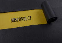 Torn black paper revealing the word 'MISCONDUCT' on yellow paper