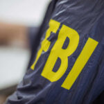 Ex-FBI Chief INDICTED Over Assassination Threat? Person wearing FBI jacket, letters in yellow.