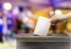 Election Authority Battle EXPLODES Across America Hand placing ballot in voting box.