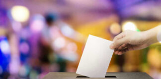 Hand placing ballot in voting box.