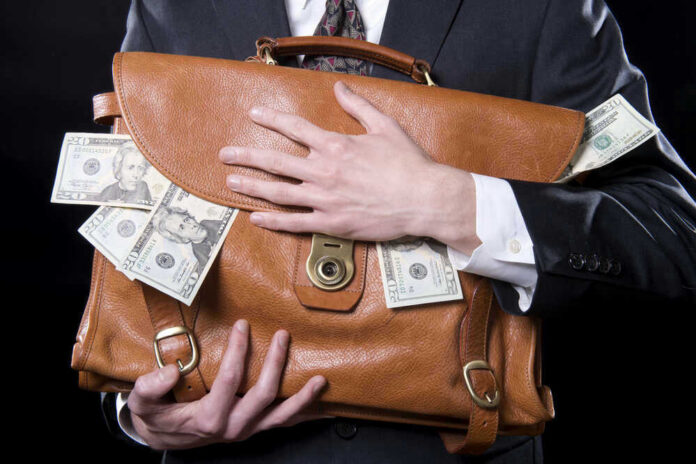 shutterstock_133129220-1.jpg Person clutching leather bag with money sticking out.