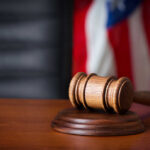 Murder Conviction Overturned — Jury Tampering! A wooden gavel resting on a sound block with an American flag in the background