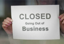 CENTURY-OLD Site SHUTDOWN – Employees Shattered! A person holding a sign that reads 'CLOSED Going Out of Business'