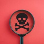 NEO-NAZI’S Santa Plot: Poisoned Candy Horror Magnifying glass focusing on a skull and crossbones symbol against a red background